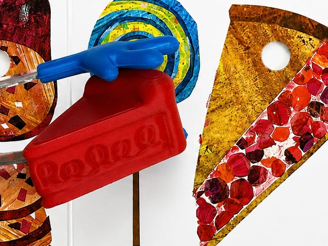 A close-up of a red plastic pizza slice-shaped container or mold with a blue handle, shown alongside other colorful textured craft-like pieces on a white background.
