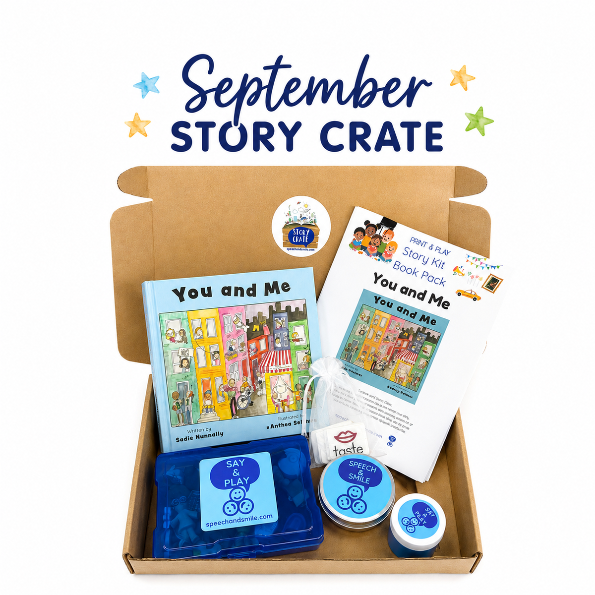A cardboard gift box labeled 'September Story Crate' on a white background, filled with children's story materials including a book titled 'You and Me,' a book pack, a blue activity tray, small round containers, and a small bag in a clear bag.