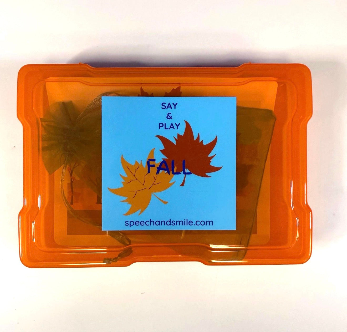 An orange plastic storage container on a white background, containing autumn-themed speech and play cards and a blue card reading 'SAY & PLAY FALL speechandsmile.com' with fall leaf graphics.